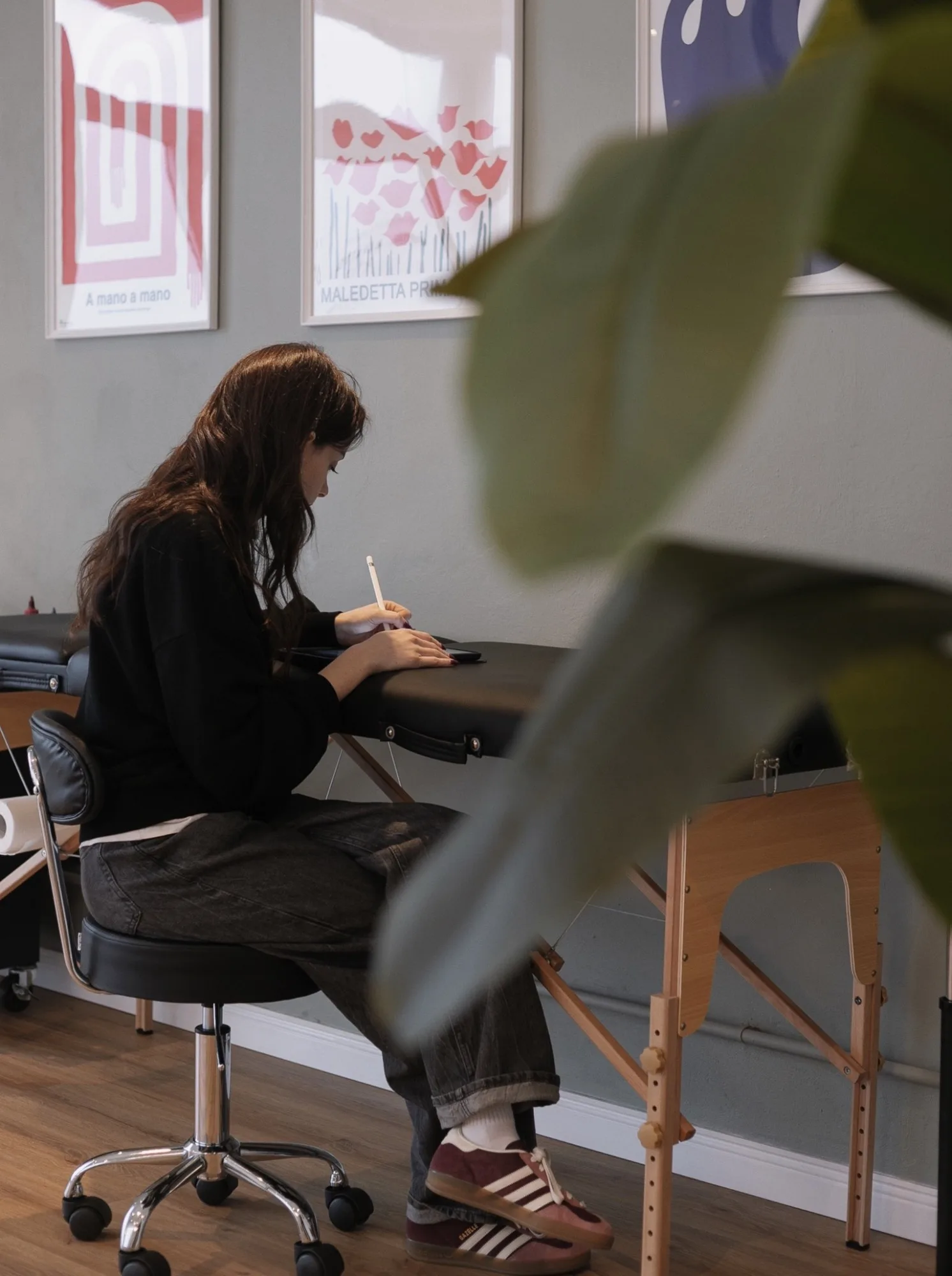 Ottavia disegna sull’iPad, seduta al lettino dello studio, sotto i manifesti